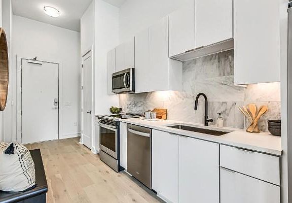 Sleek white kitchen with quartz counter tops, big sink and plenty of cabinets with a large wood shelved pantry