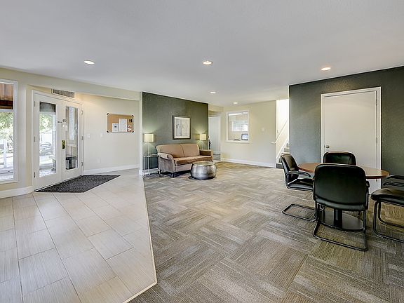 Leasing office lounge area with a sofa, chairs, and tables.