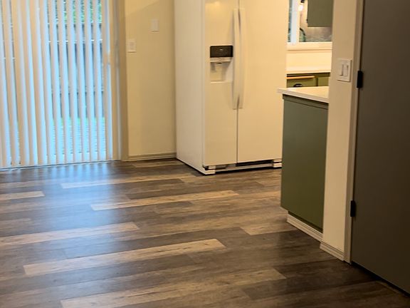 Looking from the living room near front door across dining area into kitchen. (new lighting, new refrigerator, all new matte black hinges, knobs, drawer pulls, and sanded and painted cabinets). 2025