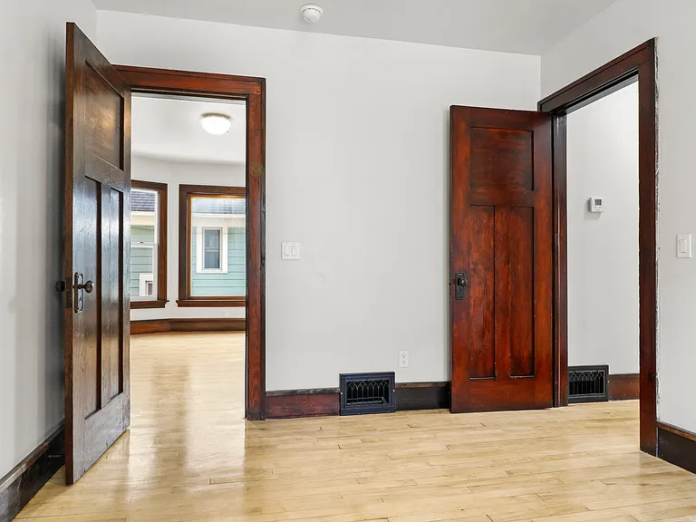 Shot empty from the first bedroom into dining room left and hallway to kitchen and back bedroom right.
