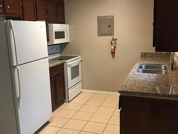 Kitchen with refrigerator, flat-top stove, built in microwave, and double stainless steel sink.