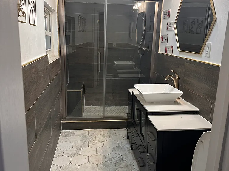 Remodeled modern bathroom featuring a double-sink vanity and a spacious walk-in shower with a built-in seat for added comfort and convenience.