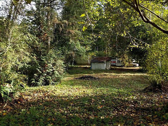 Photo from creekside tool shed is in view and trailer is obscured behind it. Currently, there is a storage container that takes up much of this area. There is an immature semi-dwarf fruit orchard to the right of the frame (street side)9