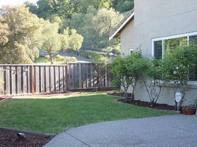 Backyard with lawn and patio area and raised planter bed.
