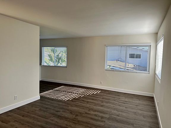 Living room with room for dining table, new high-end flooring throughout. New window coverings, and new screens. Light and airy.
