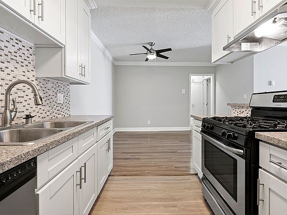 Custom tiled kitchen with stainless steel sink, oven, and fixtures.