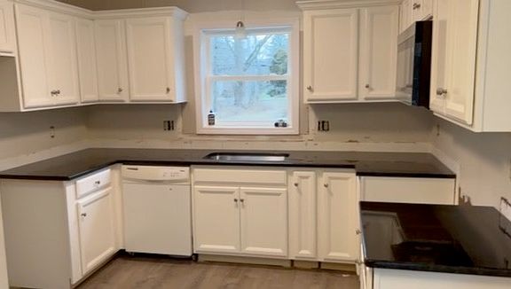 Kitchen with granite countertops, kitchen cabinets, Maytag dishwasher, microwave, electric range, refrigerator.