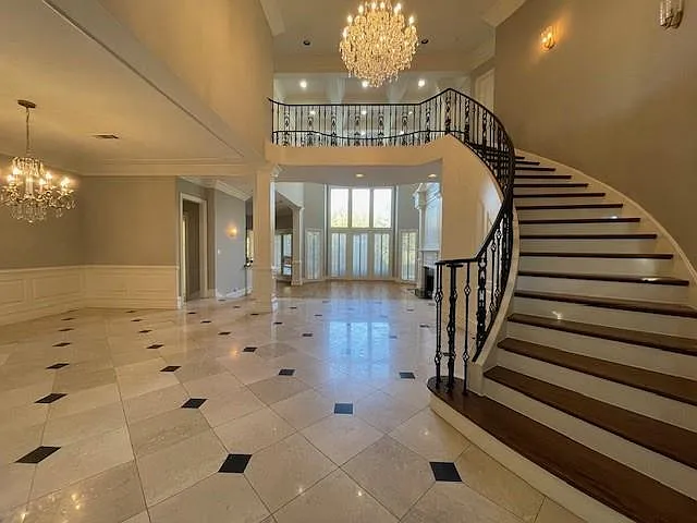Foyer featuring a chandelier, a decorative wall, a wainscoted wall, ornamental molding, and stairway