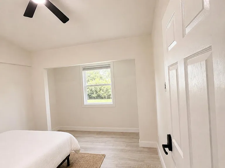 Spacious bedroom with ceiling fan, easy-care flooring, and a window overlooking greenery for comfortable everyday living.