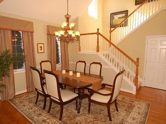 Formal Dining Room with white painted chair rail and grand chandelier overlooks dramatic staircase.