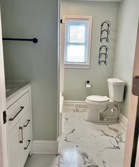 Bathroom has additional shelving behind the door. shower/tub combo