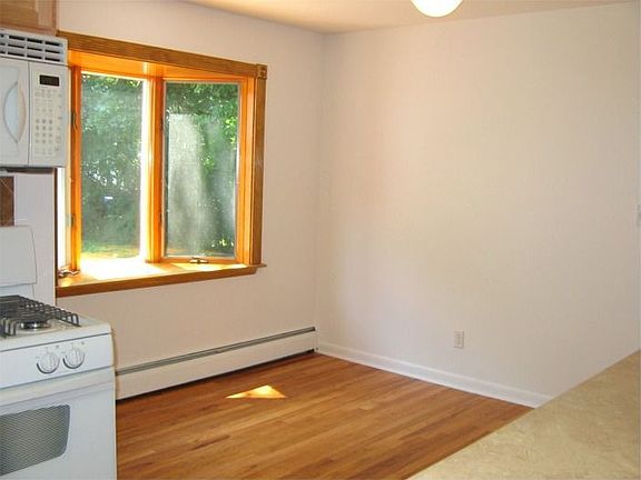 Kitchen Dining Area w/Hardwood Floor & Bay Window overlooking Backyard