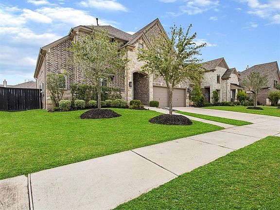 The curb appeal is incredible with brick and stonework surrounding the covered front porch, beautiful elevation, and meticulously landscaped yard.