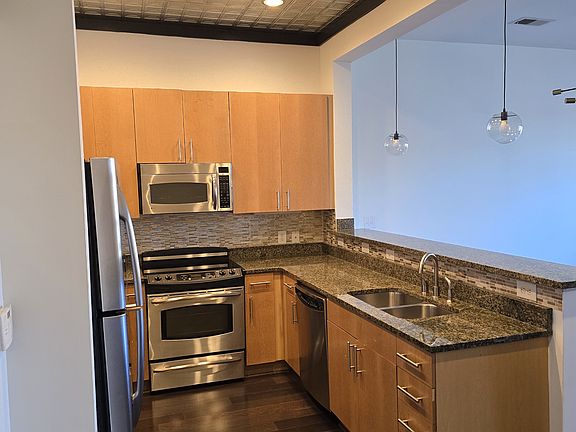 Open kitchen with stainless steel appliances, granite counter tops, unique tin ceilings