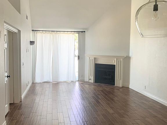 Spacious, light, and bright living room with high ceilings, ceiling fan/light combo and custom bulb fixtures over breakfast bar/dining area