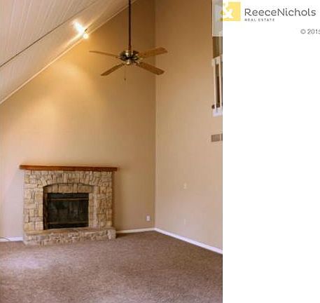 Living room with vaulted ceiling and fireplace and newer carpet.
