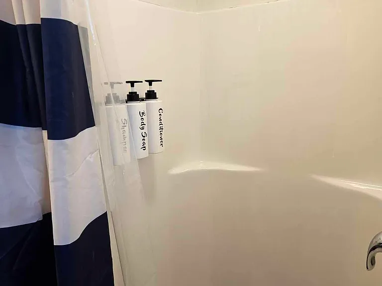 Half shower next to stackable washer and dryer.