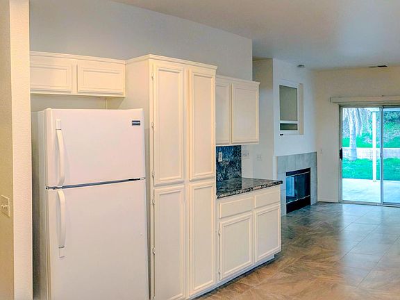 Granite counter tops, refrigerator, Onyx Sand matte porcelain tile floor, gas fireplace with stone logs, new Swiss Coffee color paint with satin sheen finish. Low-maintenance backyard with covered patio. (June 2025)