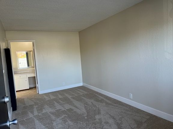 View from front door. In the back of photo is a built in vanity / desk area, entry to bathroom with shower over tub and a large walk in closet.