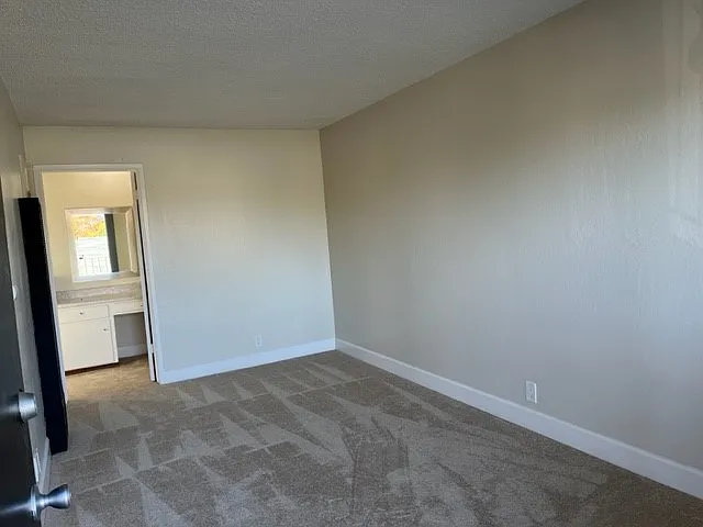 View from front door. In the back of photo is a built in vanity / desk area, entry to bathroom with shower over tub and a large walk in closet.