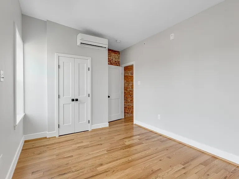 The larger bedroom has two large windows and a storage closet.