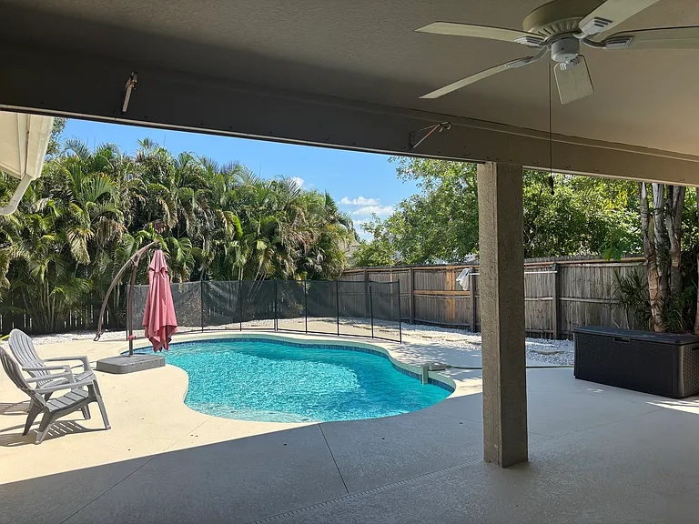 Outdoor covered patio area with view of pool and backyard there is a small pad on left side away from house for grilling area