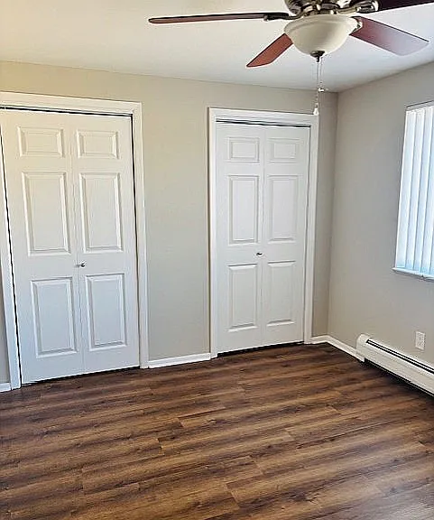 Charming bedroom featuring elegant hardwood floors, dual closets, and a ceiling fan for comfort.