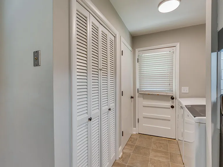 Laundry room with washer and dryer, door leading to backyard.
