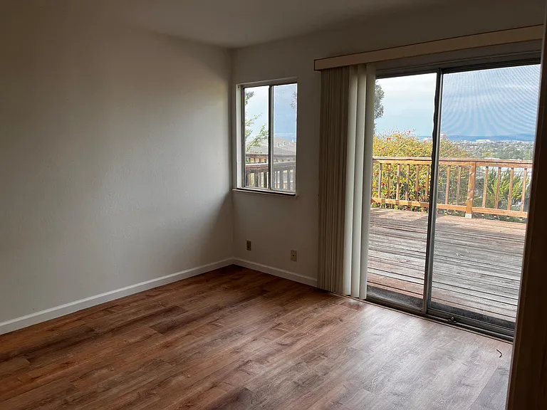 This bedroom has a million-dollar view of the San Francisco Bay and the San Mateo Bridge, and newly installed hard flooring.