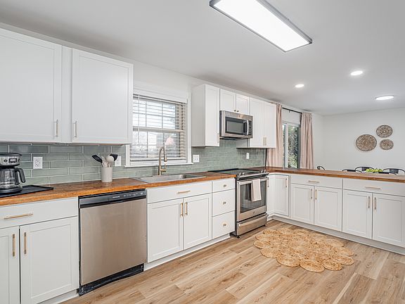 Kitchen with tile backsplash, butcher block countertop, new cabinets, appliances, and new flooring