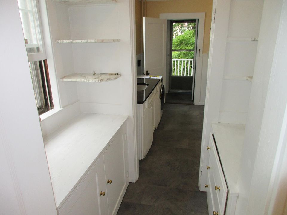 Pantry connecting dining room to kitchen with a swinging door. Cabinets, drawers and shelves for storage.