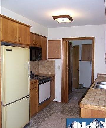 A step saver kitchen with oak cabinets. The appliances come with the home.
