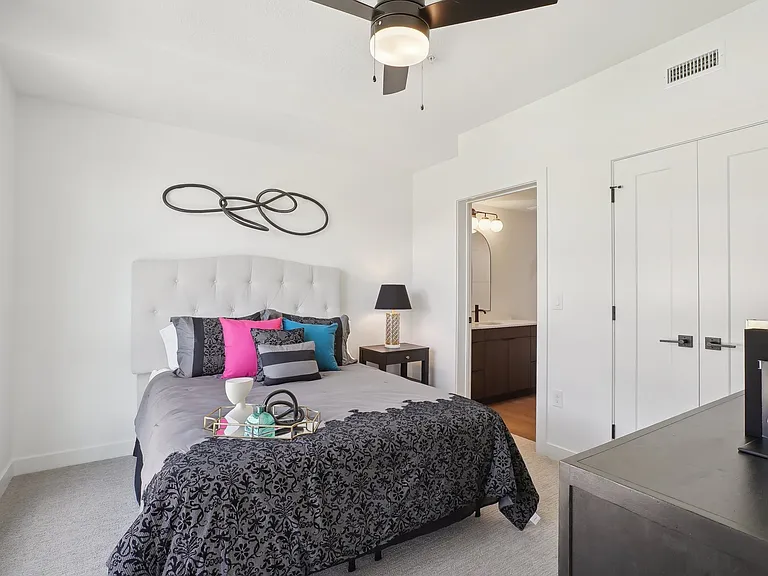 Liberty Duet Apartments, Salt Lake City, Utah; A bedroom with a bed, a ceiling fan, and a nightstand with a lamp.