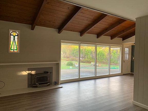Light and bright living room with great natural light, vaulted ceilings, wood burning fireplace, and hard surfaces.