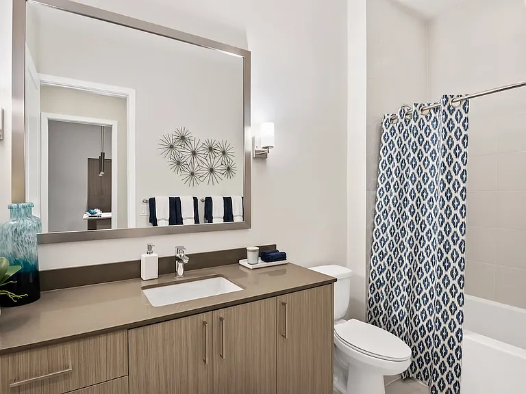 Bath with grey quartz countertop and hard-surface vinyl plank flooring