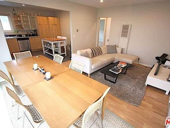 Living room and kitchen view with previous tenant's furnishings.