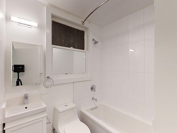 Bathroom with bathtub, showerhead, toilet, sink, mirror, and window