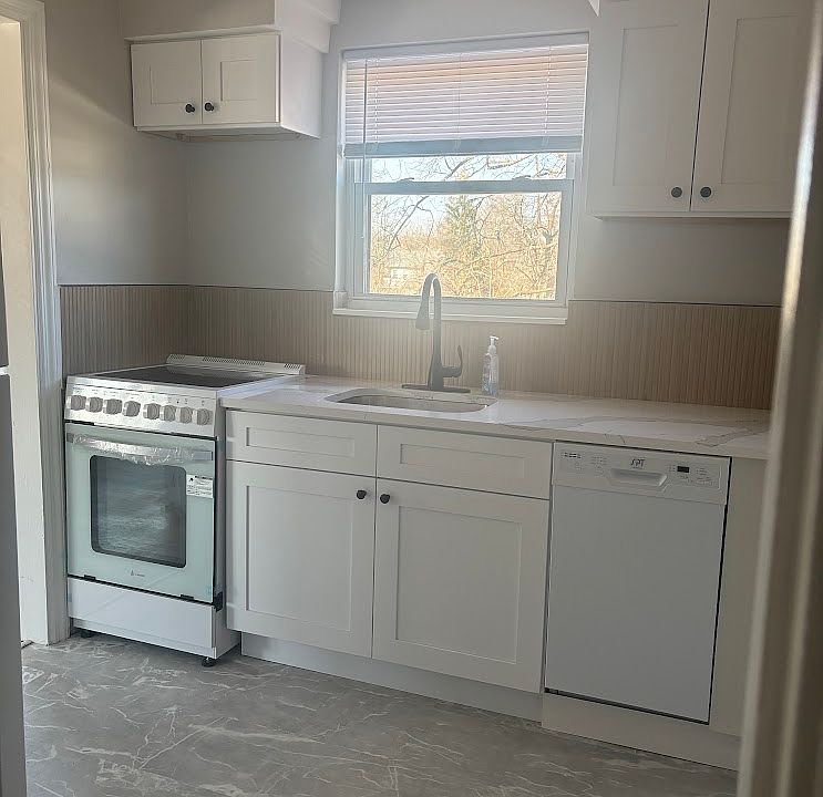 Kitchen with new stove, dishwasher, quartz top, refrigerator. New tile backsplash.