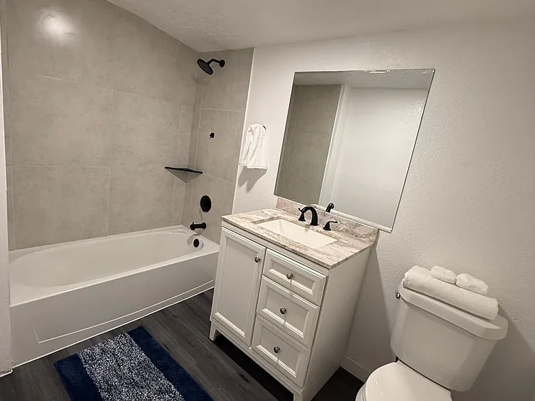 Full bathroom with tub/shower combo, tiled surround, and a single-sink vanity with ample storage and a large mirror.