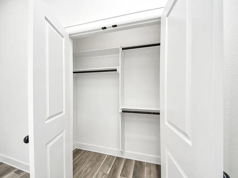Spacious walk-in closet with double hanging rods and built-in shelving for organized clothing and extra storage.