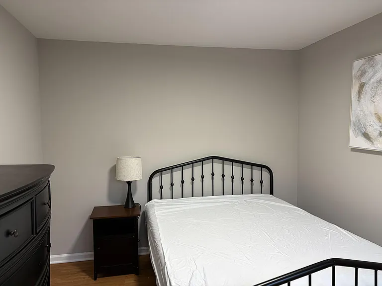 Furnished bedroom with a full-size bed, nightstand and lamp, plus a dresser for convenient everyday storage.