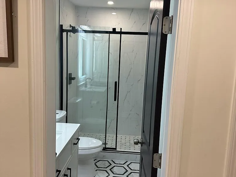 Updated bathroom with a glass-enclosed shower, patterned tile flooring, and a vanity with storage.