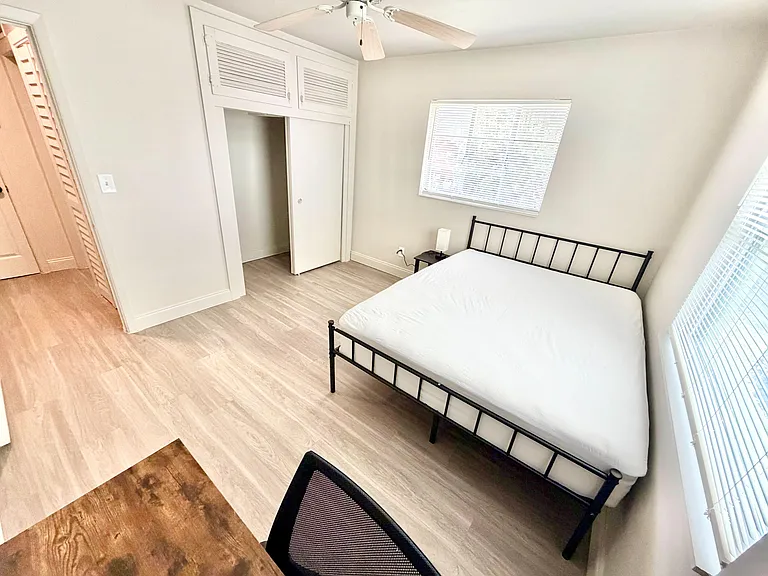 Furnished bedroom with a bed, ceiling fan, and a built-in closet, plus windows with blinds and easy-care flooring.