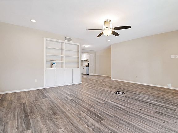 Spacious room featuring wood-finish flooring, recessed lighting, and a ceiling fan
