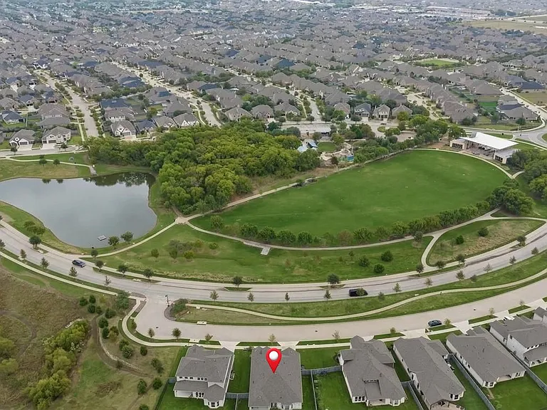 Aerial view of the home marked by the pin and showcasing the gorgeous green space in front including park, space, green belt, lawn, community pond, resort style pool, playground and pavillion.