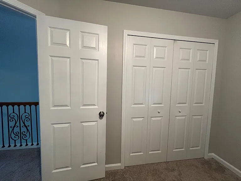 Carpeted hallway/landing with double sliding closet doors for convenient storage near the upstairs rooms.