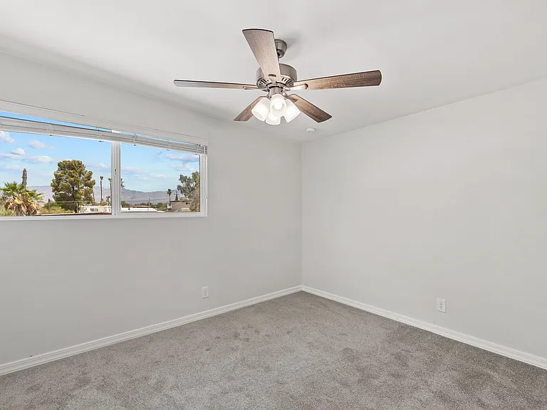 Comfortable third bedroom featuring a ceiling fan and scenic window view.