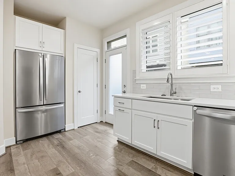 Stainless steel refrigerator and freezer, includes ice maker and water dispenser. Door leads to back patio.