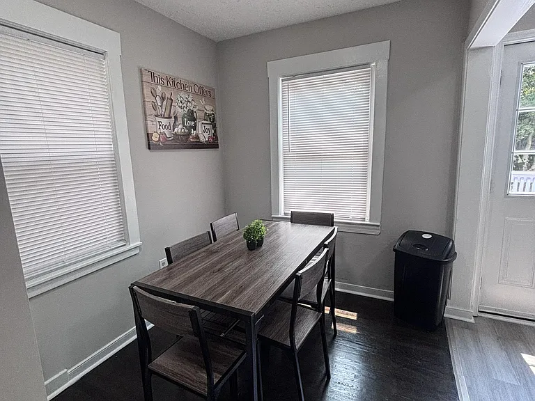 Dedicated dining area with a full-size table, easy-care flooring, and two windows plus a door for convenient outdoor access.