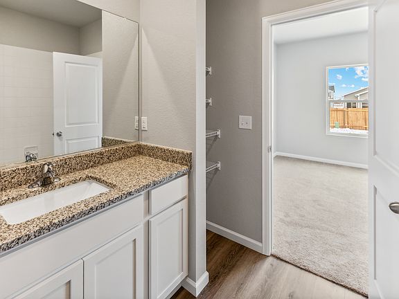 Master bathroom with storage shelves and white cabinets.